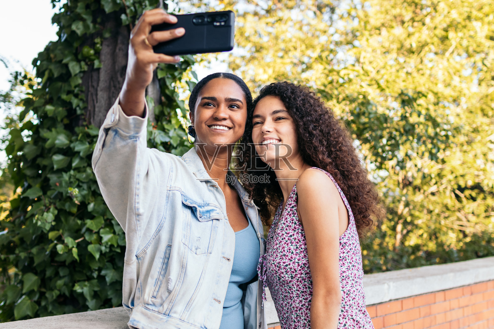 快乐的女性在户外用智能手机自拍照片摄影图片