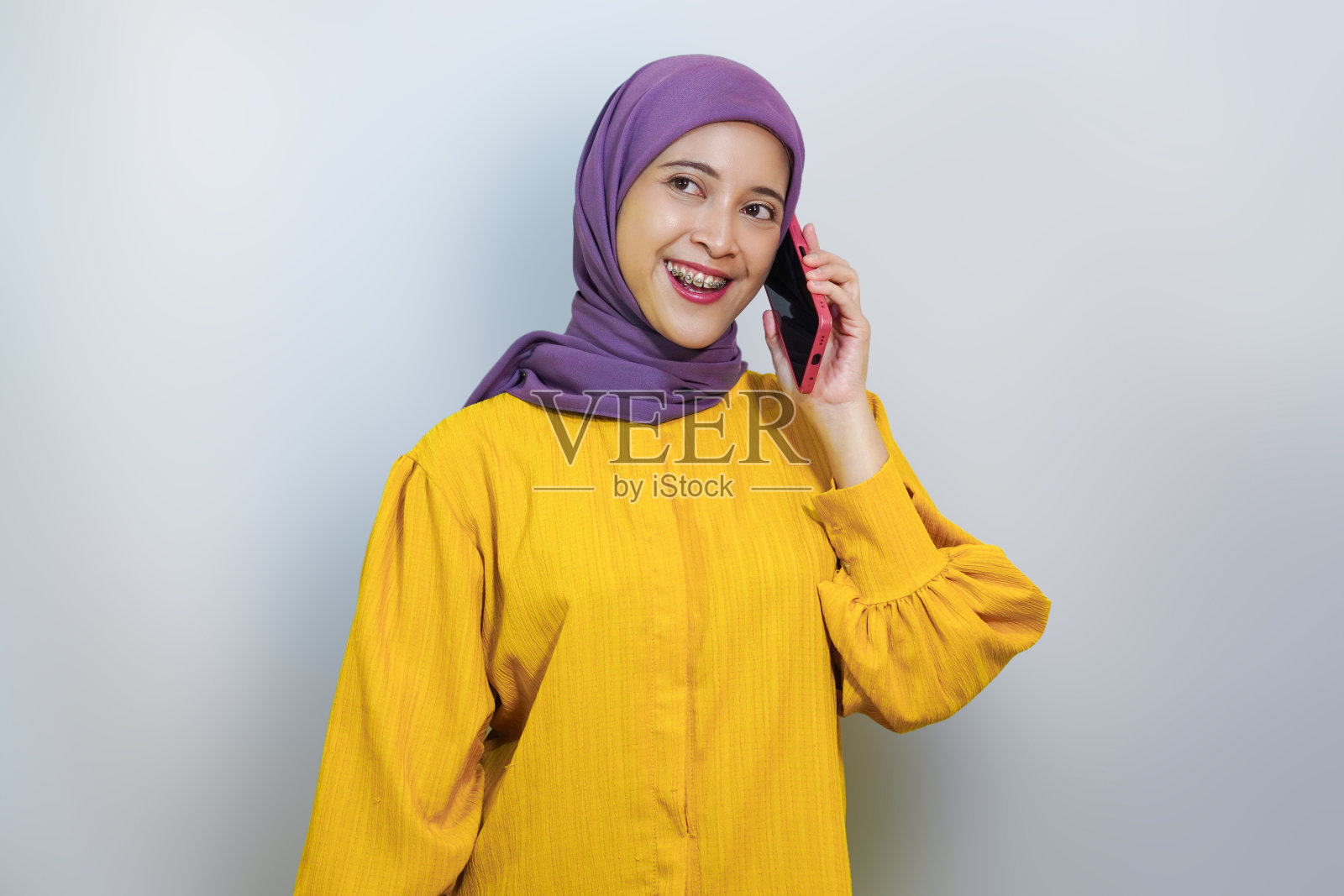 年轻的亚洲穆斯林妇女穿着黄色的衣服，孤立在白色的背景上照片摄影图片