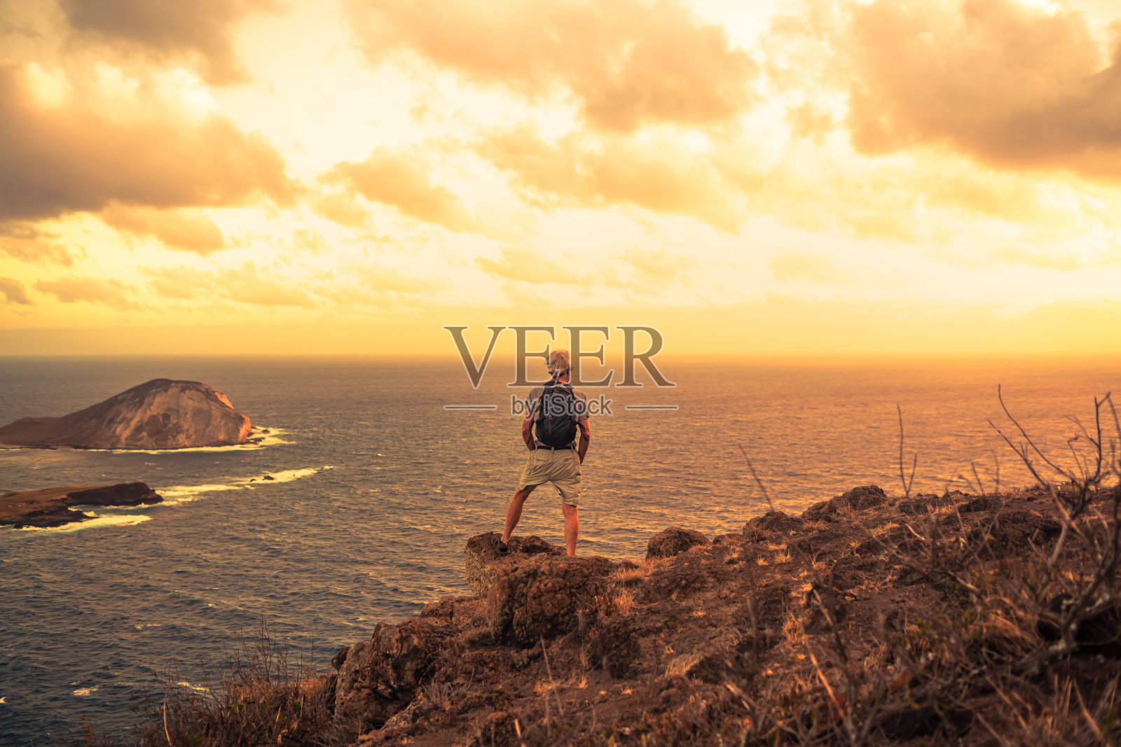 资深男性徒步旅行者在山顶欣赏美丽的日落。照片摄影图片