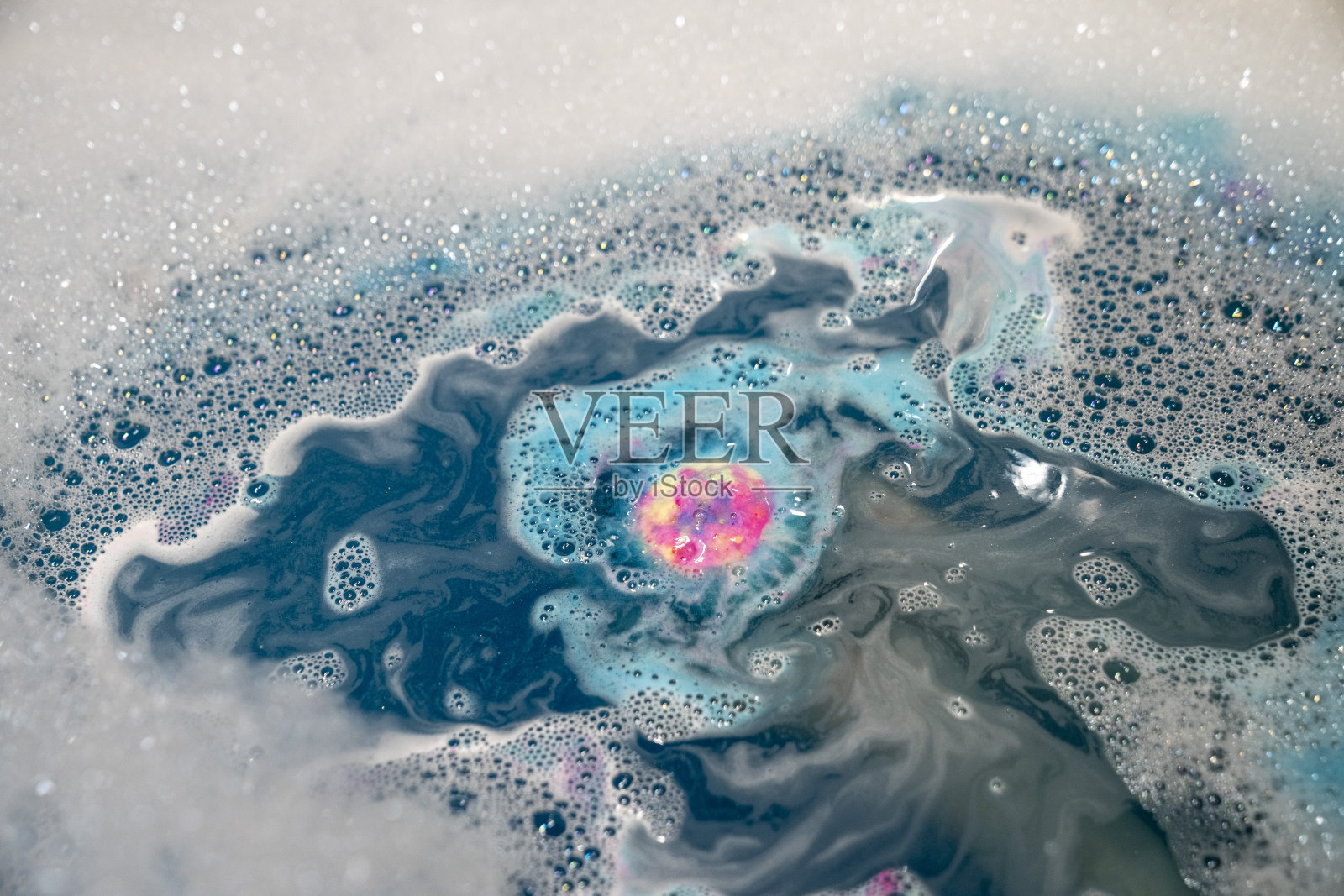 女性的手，水溶性蓝色，黄色，粉色，沐浴炸弹，气泡水，近距离。照片摄影图片