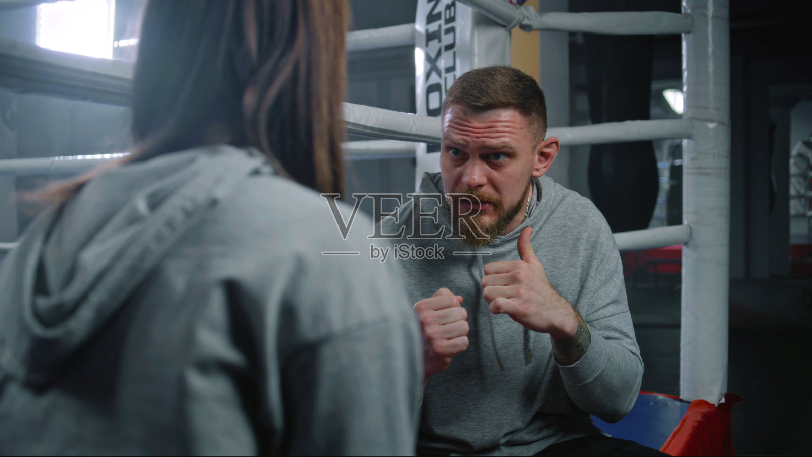 女拳击手坐在拳击台上和男教练谈论拳击照片摄影图片