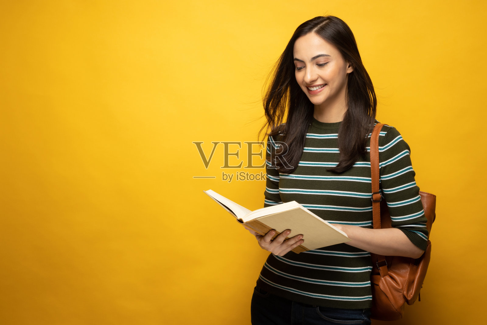 照片的年轻女子穿t恤读书孤立的黄色背景股票照片照片摄影图片