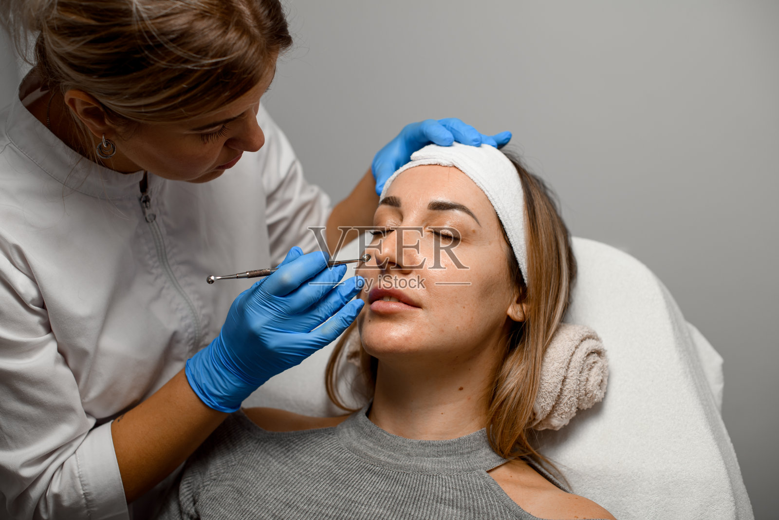 一名女美容师正在用UNO美容勺为一名年轻女子进行面部清洁照片摄影图片