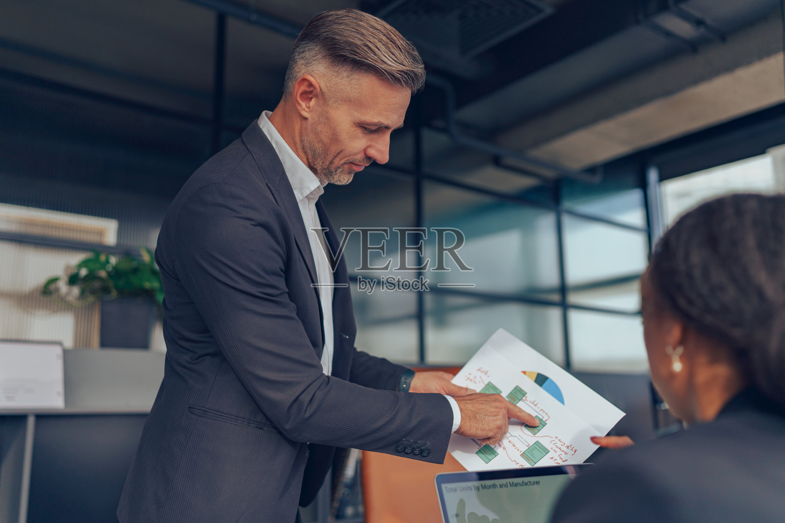 成熟的商人经理在办公室会议上拿着文件咨询客户照片摄影图片