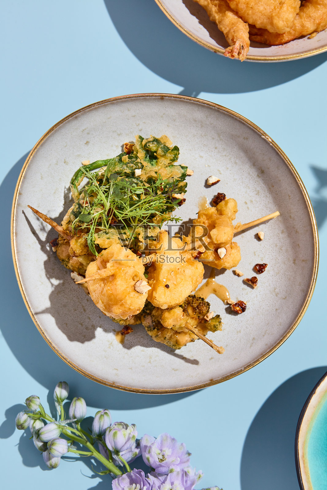 陶瓷盘上的天妇罗花椰菜和西兰花配坚果酱，辅以超现实的春天美学照片摄影图片