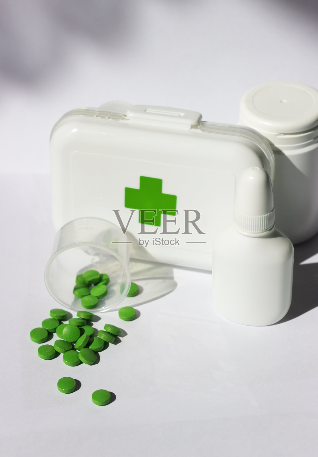 一个小急救箱，上面有药，盖子上有个十字架。附近有几瓶药。这一切都在一个白色的背景照片摄影图片