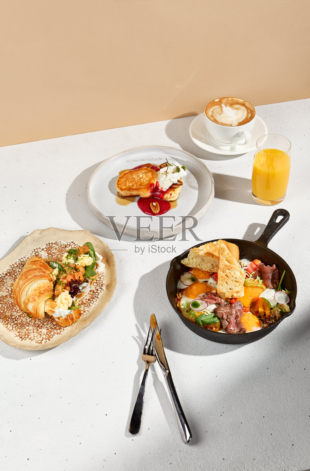 美味的早餐与鲑鱼羊角包，煎蛋，煎饼与卡布奇诺和橙汁照片摄影图片