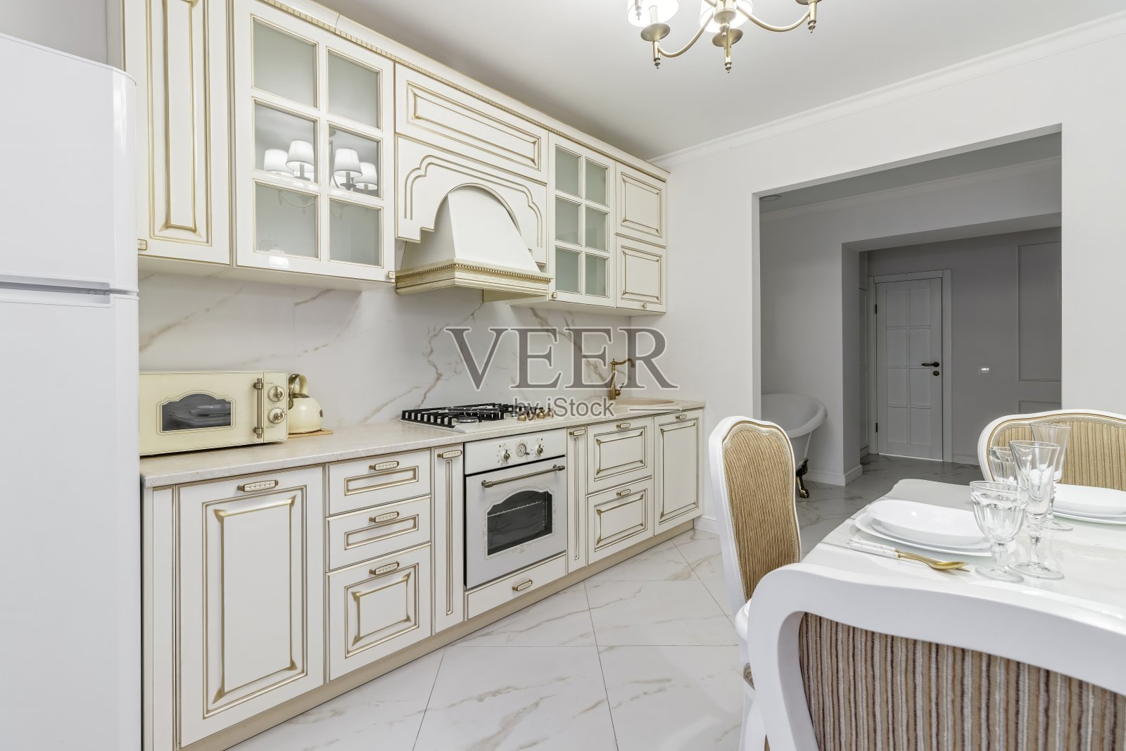 漂亮的厨房细节，白色橱柜，金色水龙头，白色大理石台面照片摄影图片