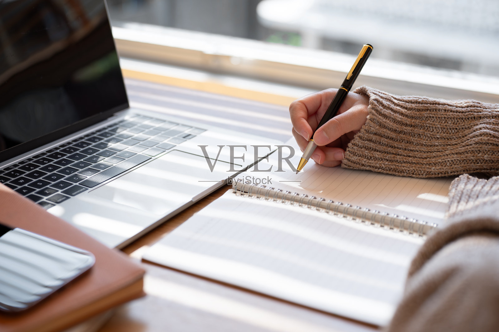 一个女人在室内用笔记本电脑写东西的特写。照片摄影图片