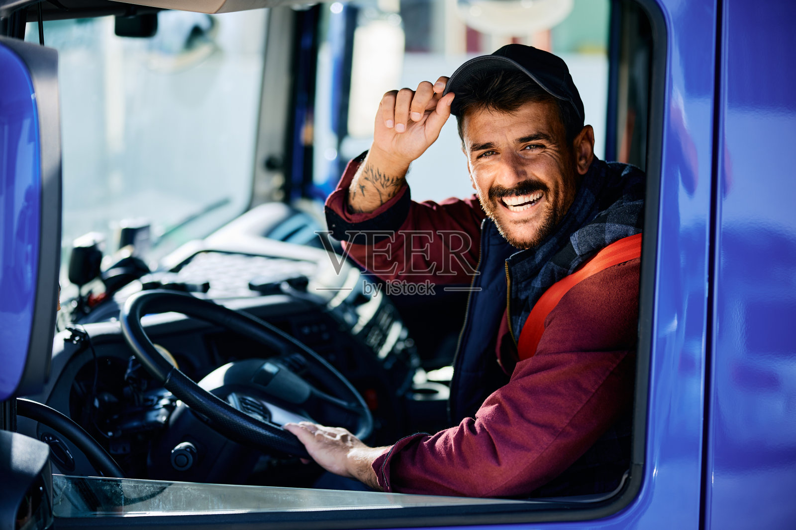 坐在卡车方向盘后面开心地看着摄像头的司机。照片摄影图片