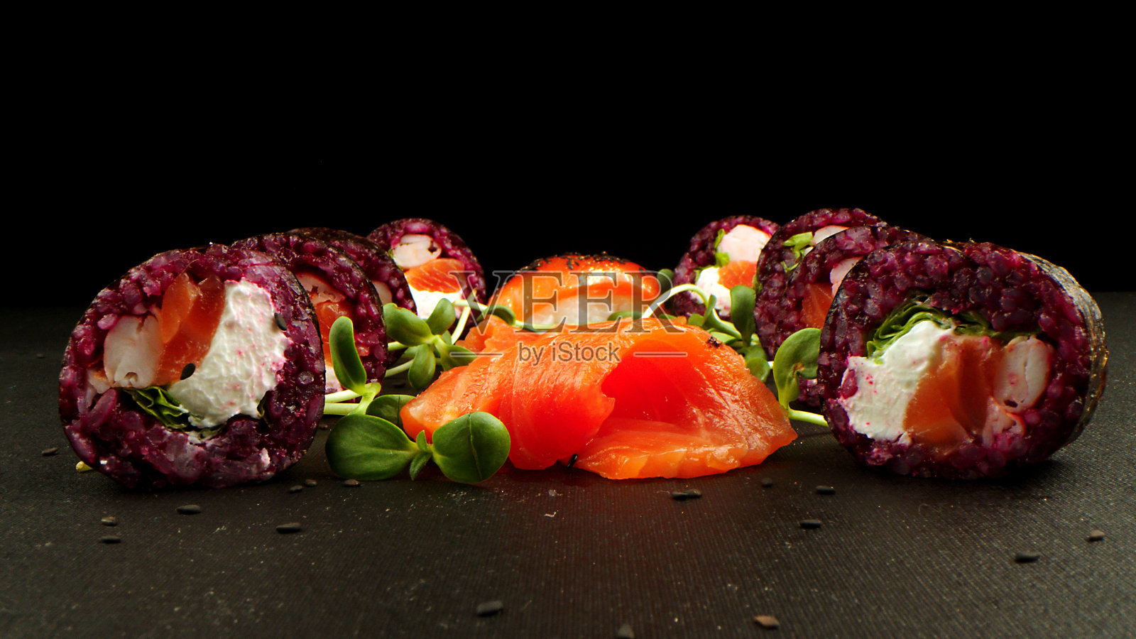 黑色背景上的绿色寿司卷。令人难以置信的新鲜寿司卷在黑暗的背景。烹饪传统的日本海鲜和鱼菜。照片摄影图片