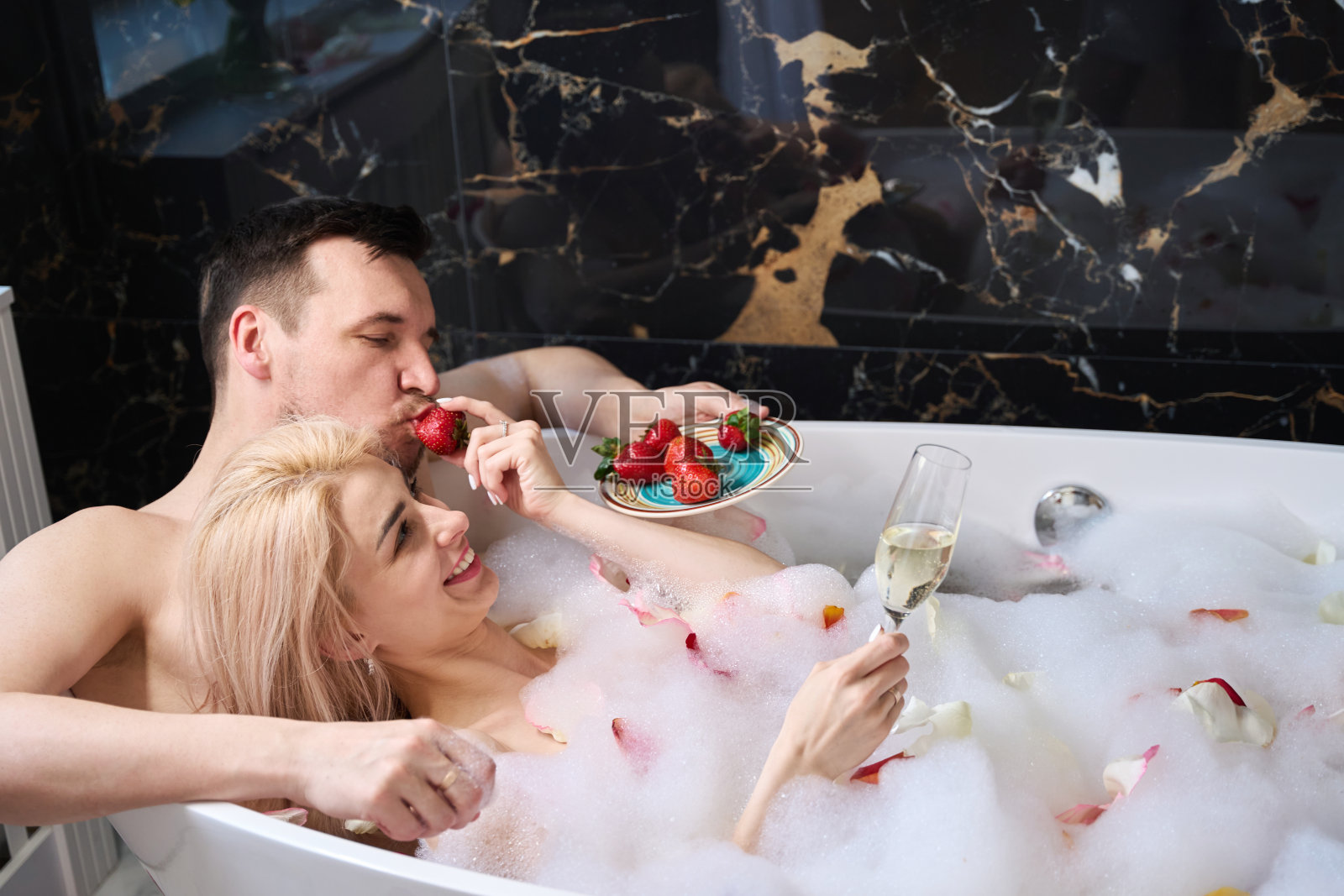 女人和男人在泡沫浴中享用草莓和香槟照片摄影图片
