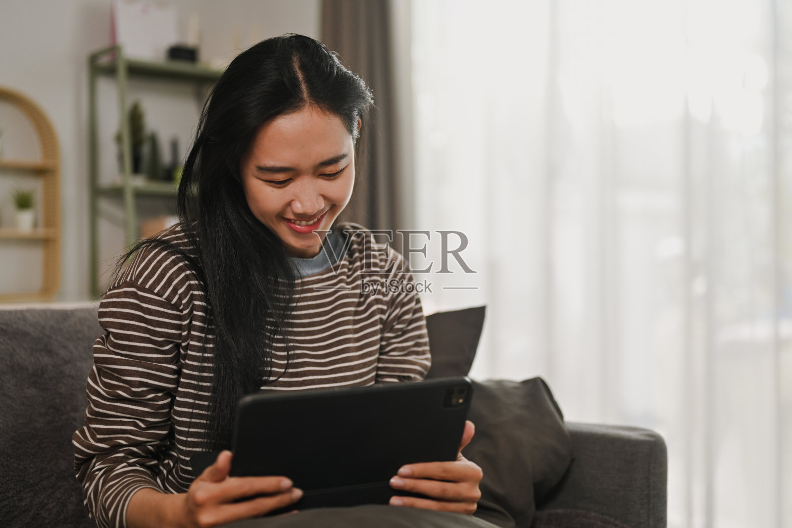 无忧无虑的年轻女子在家里上网或在平板电脑上看视频照片摄影图片