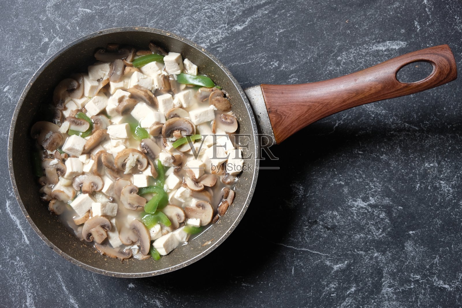 Tumis Tahu Jamur Kancing辣椒粉，炒豆腐，香菇，青椒在大理石煎锅。印尼的食物。素食菜单。健康食品。照片摄影图片