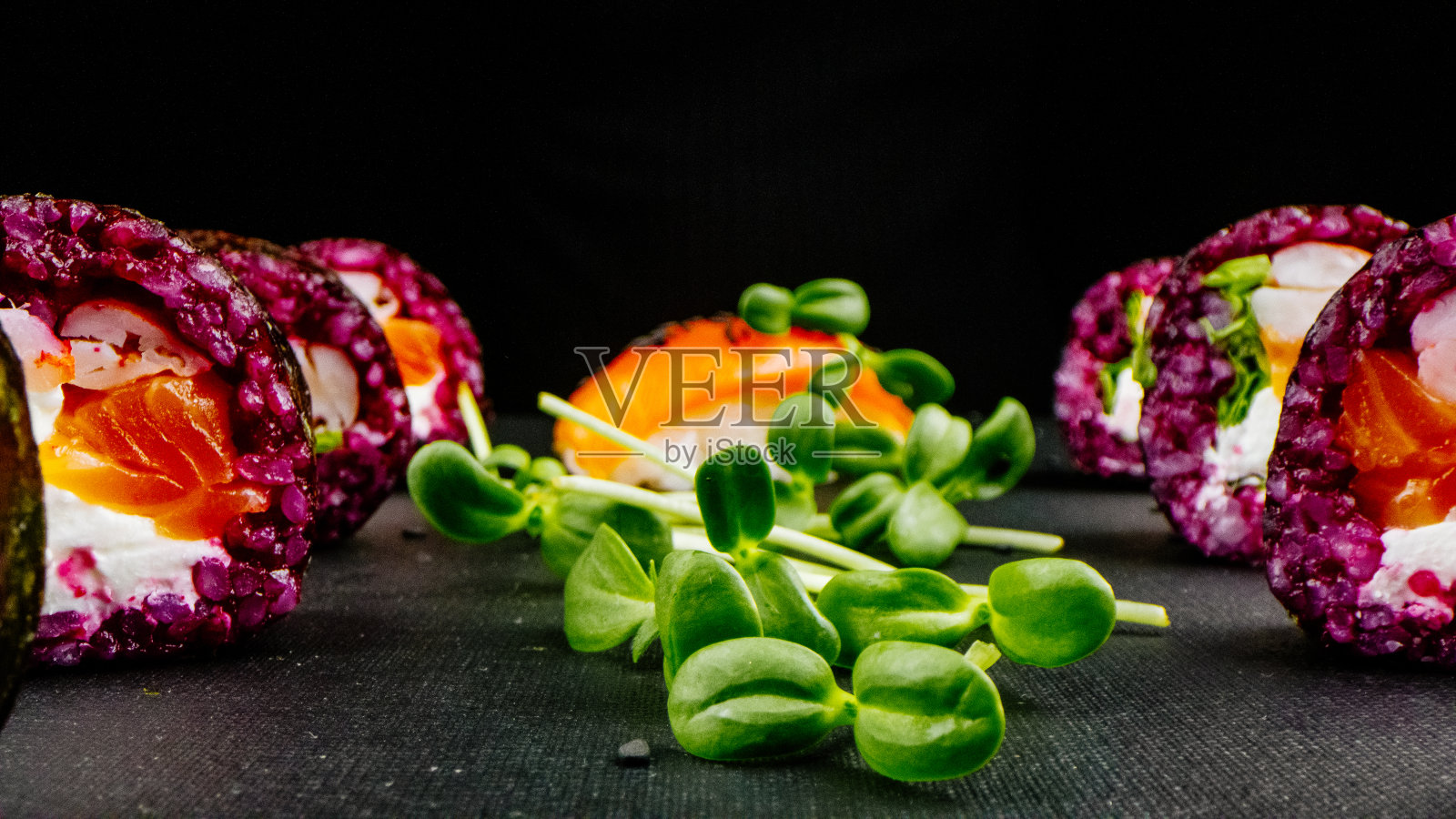 黑色背景上的绿色寿司卷。令人难以置信的新鲜寿司卷在黑暗的背景。烹饪传统的日本海鲜和鱼菜。照片摄影图片