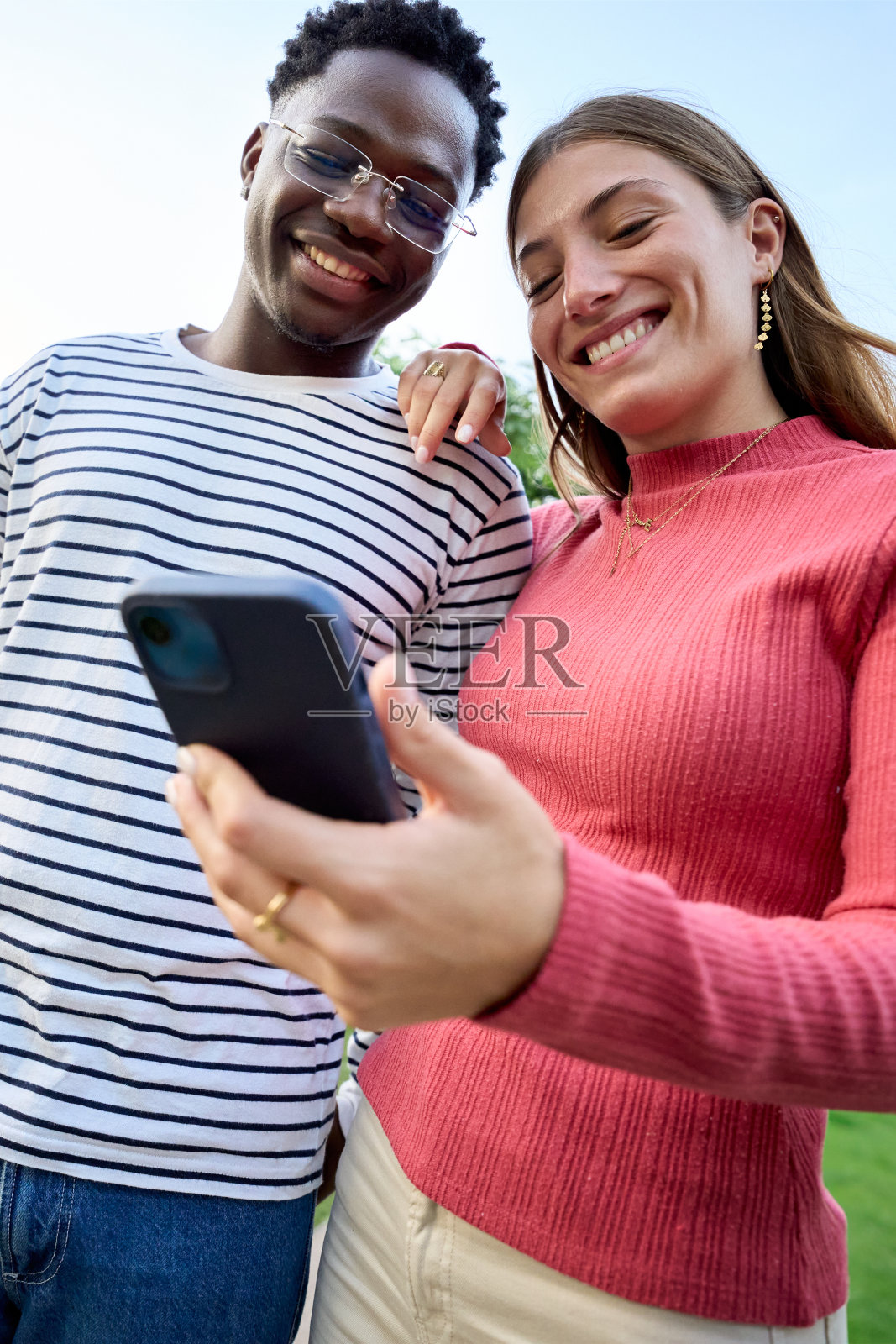 年轻的多种族夫妇微笑着拿着手里的智能手机照片摄影图片