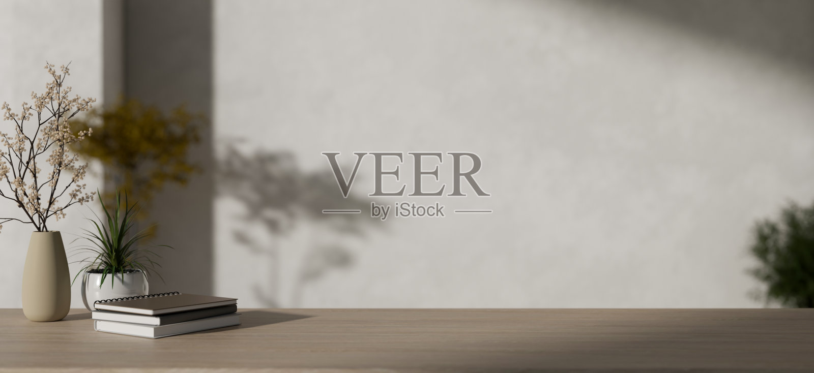 极简主义的木桌上放着书籍、花瓶和复制空间，旁边是极简主义的白墙。照片摄影图片