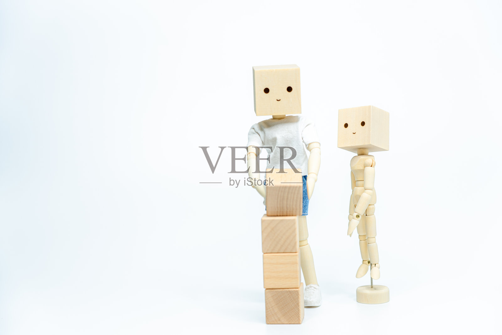 木制娃娃与木制玩具块隔离在白色背景。商业或创意概念照片摄影图片