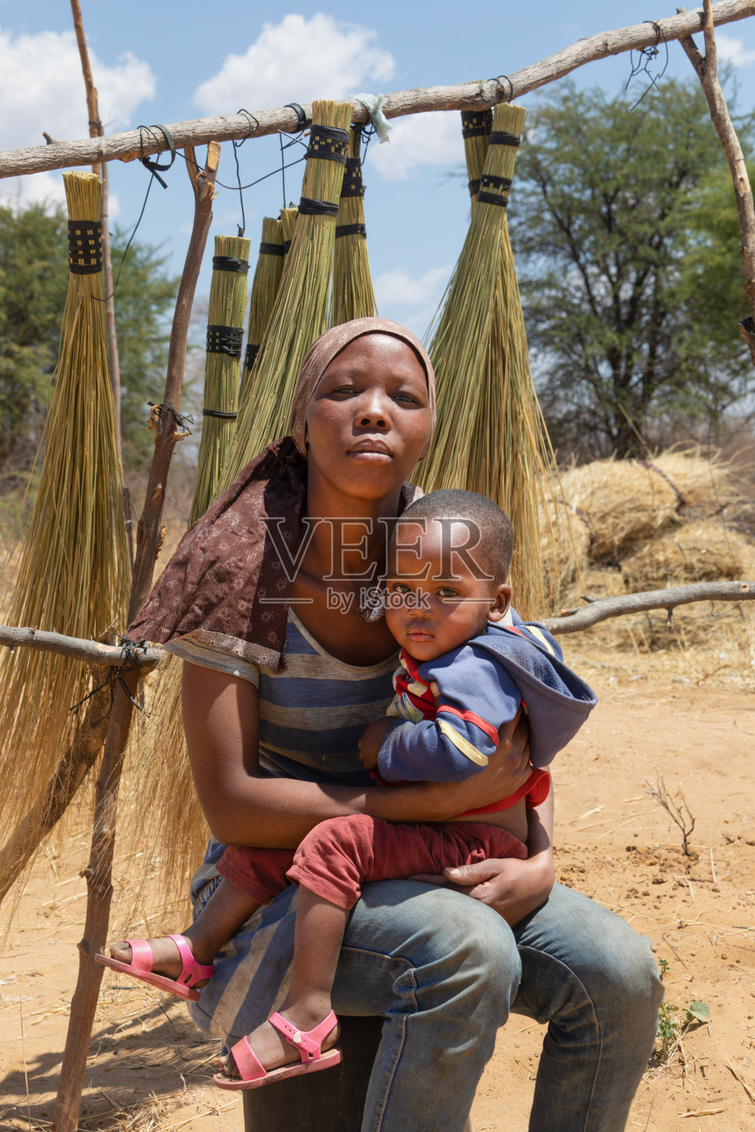 村里的非洲妇女，抱着她的孩子，在高速公路附近的街头卖扫帚照片摄影图片