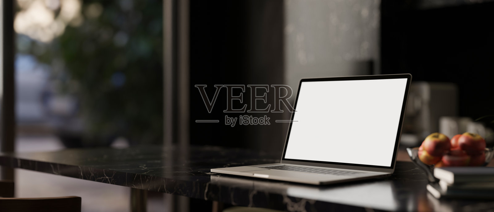 现代黑色餐厅里，黑色大理石桌面上的白屏笔记本电脑模型。照片摄影图片