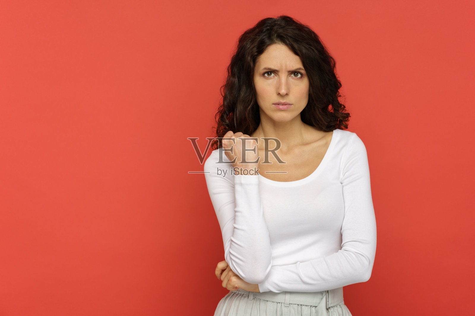 愤怒恼火的妇女的肖像向镜头展示拳头，双手合十站在红墙前以示警告照片摄影图片