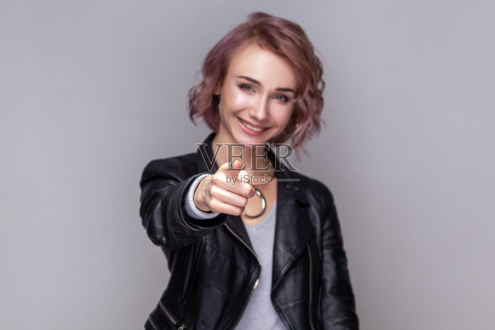 微笑满足的女人站在镜头前用食指指着，选择并需要你。照片摄影图片