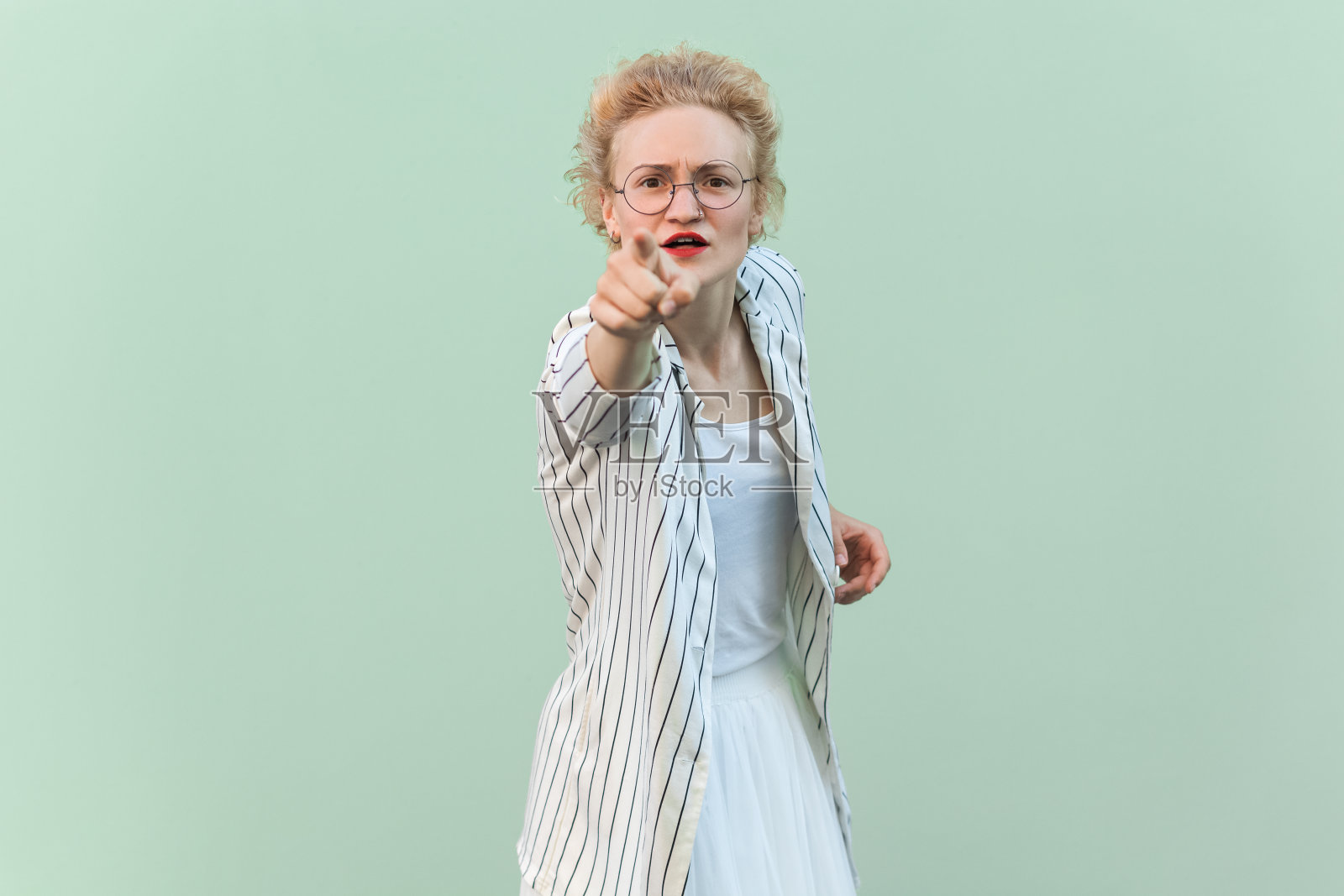 严肃严厉的金发女人用手指着镜头，选择了带着专横表情的你照片摄影图片