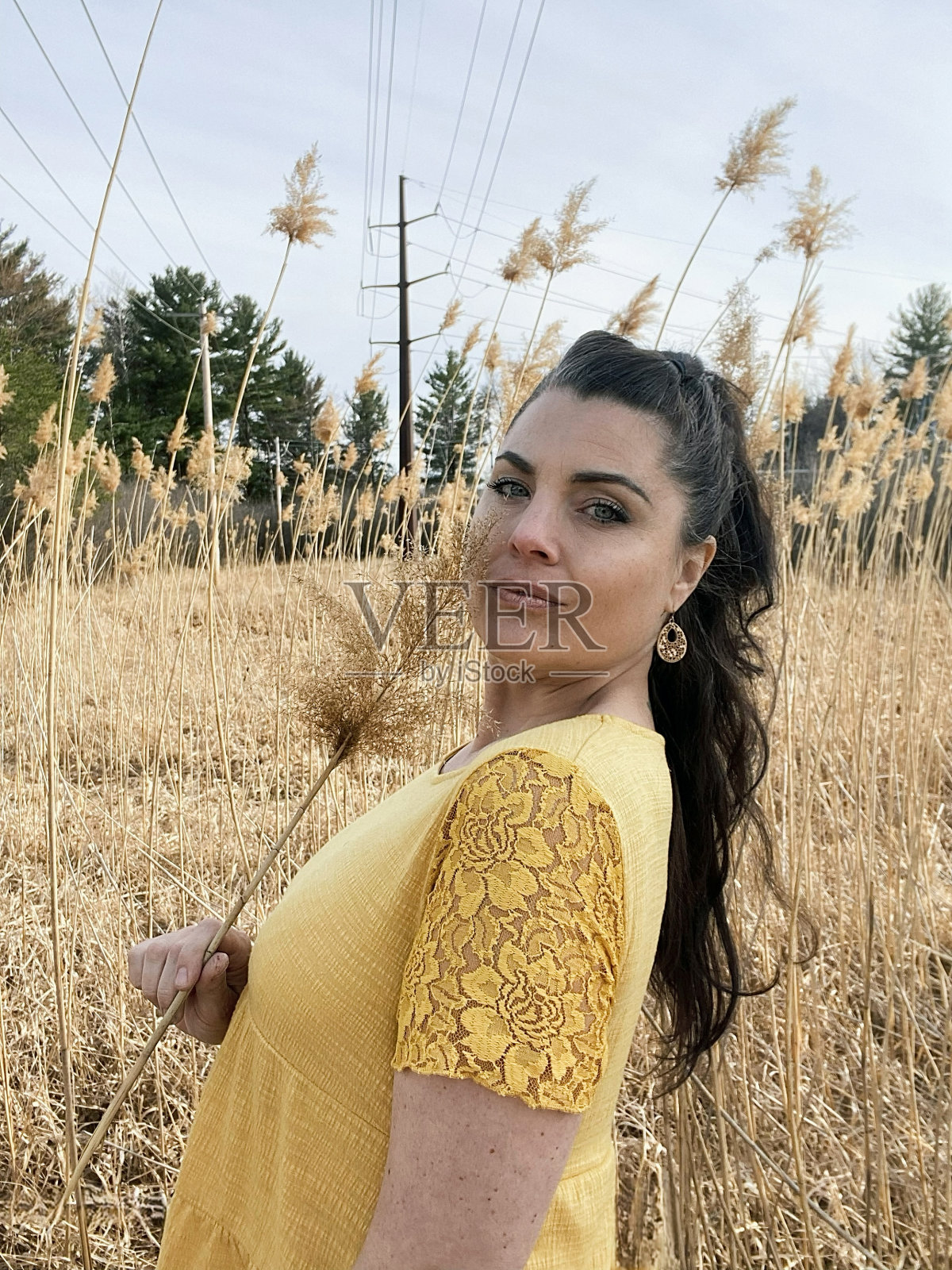 美丽的中年妇女享受大自然和自己的时间，微笑着站在高大的潘帕斯草原上。照片摄影图片