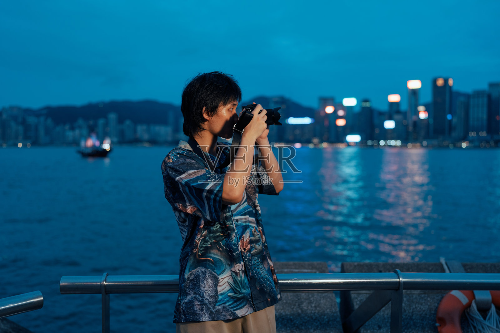 年轻的男性游客喜欢在轮渡上旅行，并在旅行中拍摄夜景照片和视频照片摄影图片
