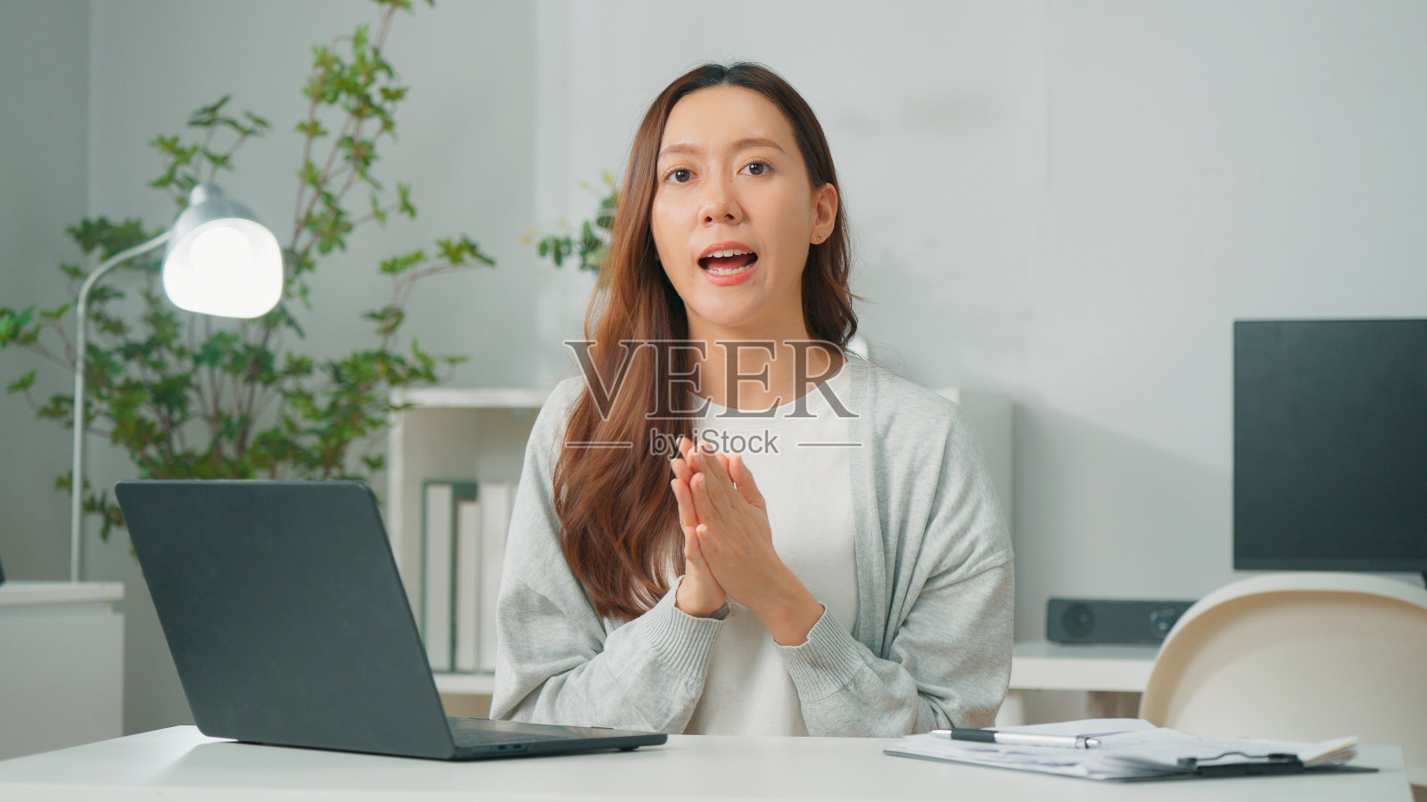 快乐的年轻亚洲女性员工或快乐的员工使用电脑笔记本电脑，与大学合作伙伴团队在互联网上进行视频会议和远程工作，自信的办公室员工在家庭办公室工作照片摄影图片