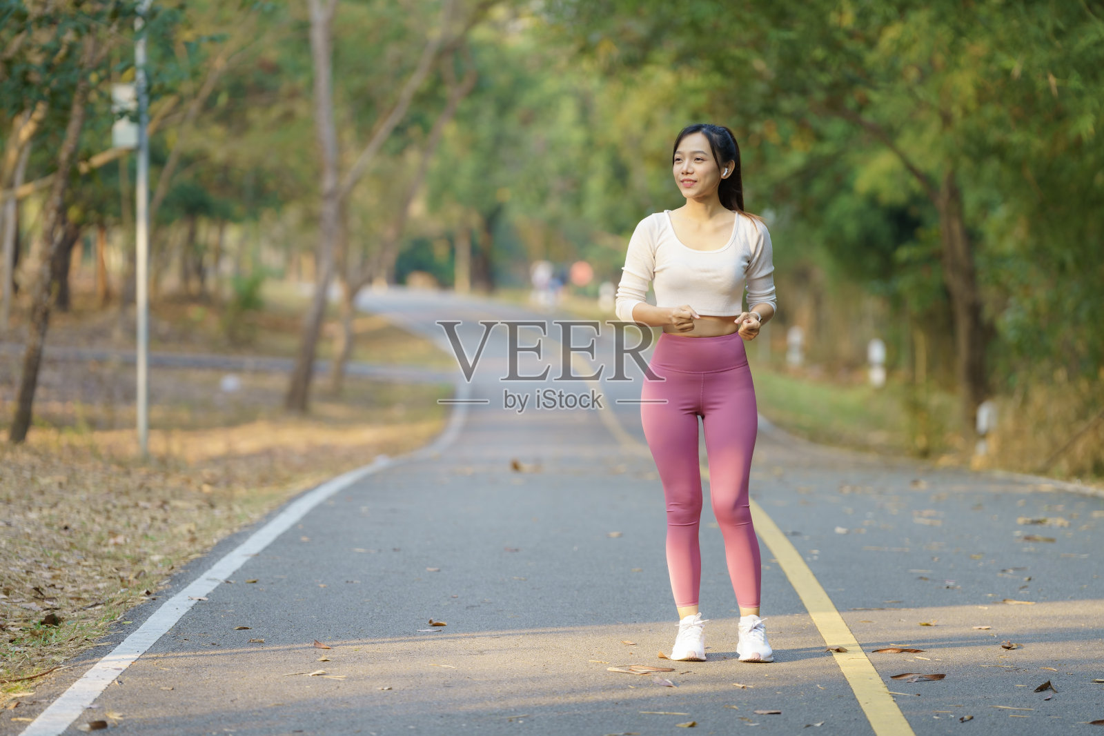 年轻的女跑步者在早上跑步前伸展手臂。女性在跑步或健身前做伸展运动来热身。健身健康生活理念。照片摄影图片