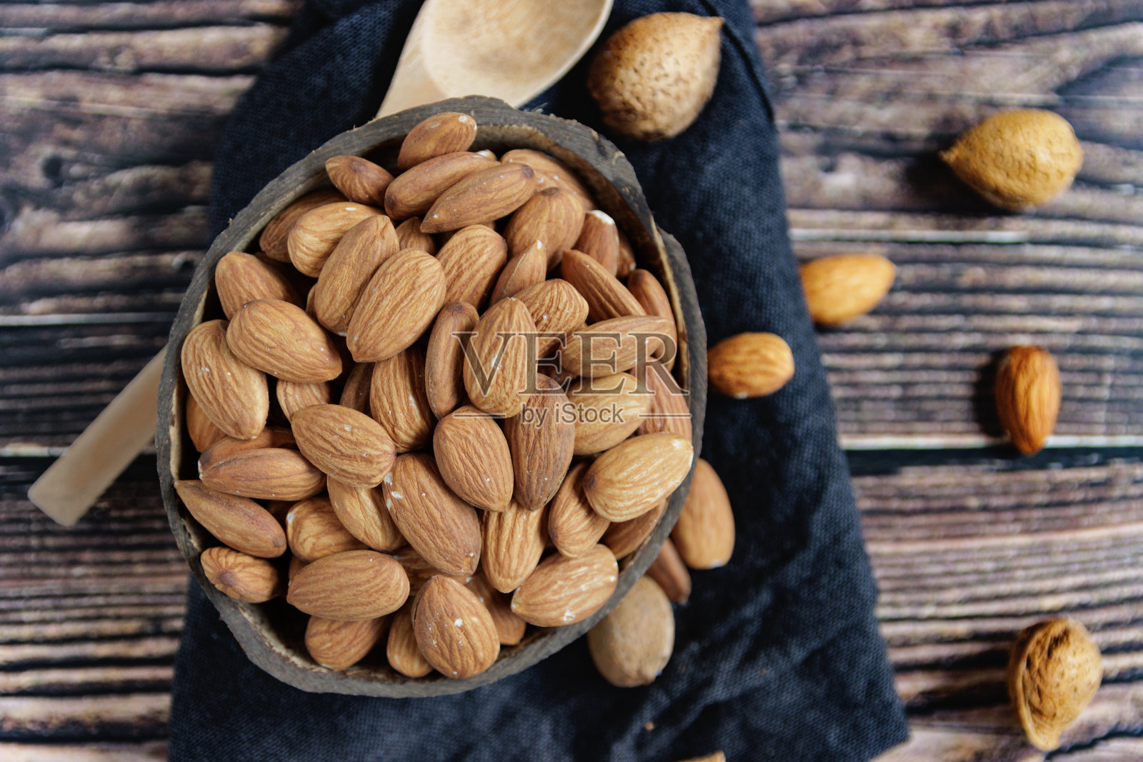 木桌上的碗里装着杏仁照片摄影图片