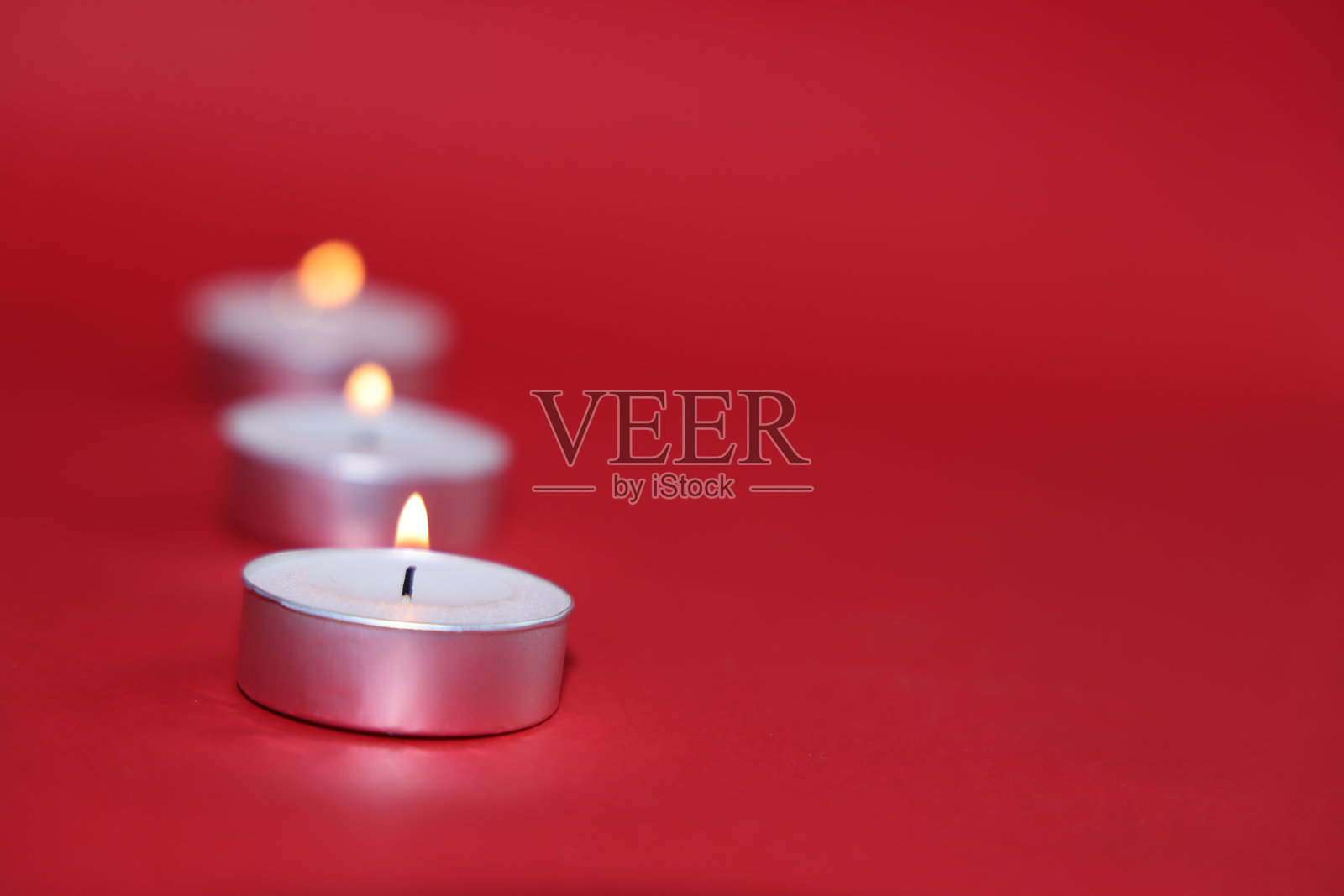 红色背景上燃烧的蜡烛。照片摄影图片