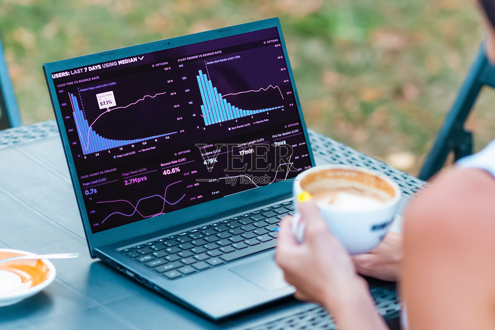 迷人的女商人坐在户外咖啡馆的桌子旁，用笔记本电脑工作。温暖的夏日。照片摄影图片