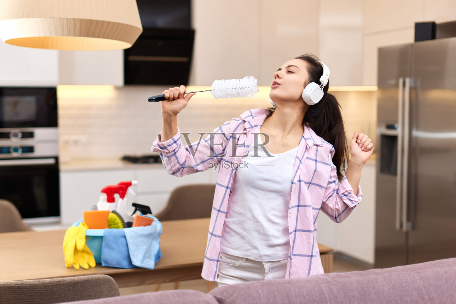 家庭主妇一边唱歌一边打扫房间，照片摄影图片