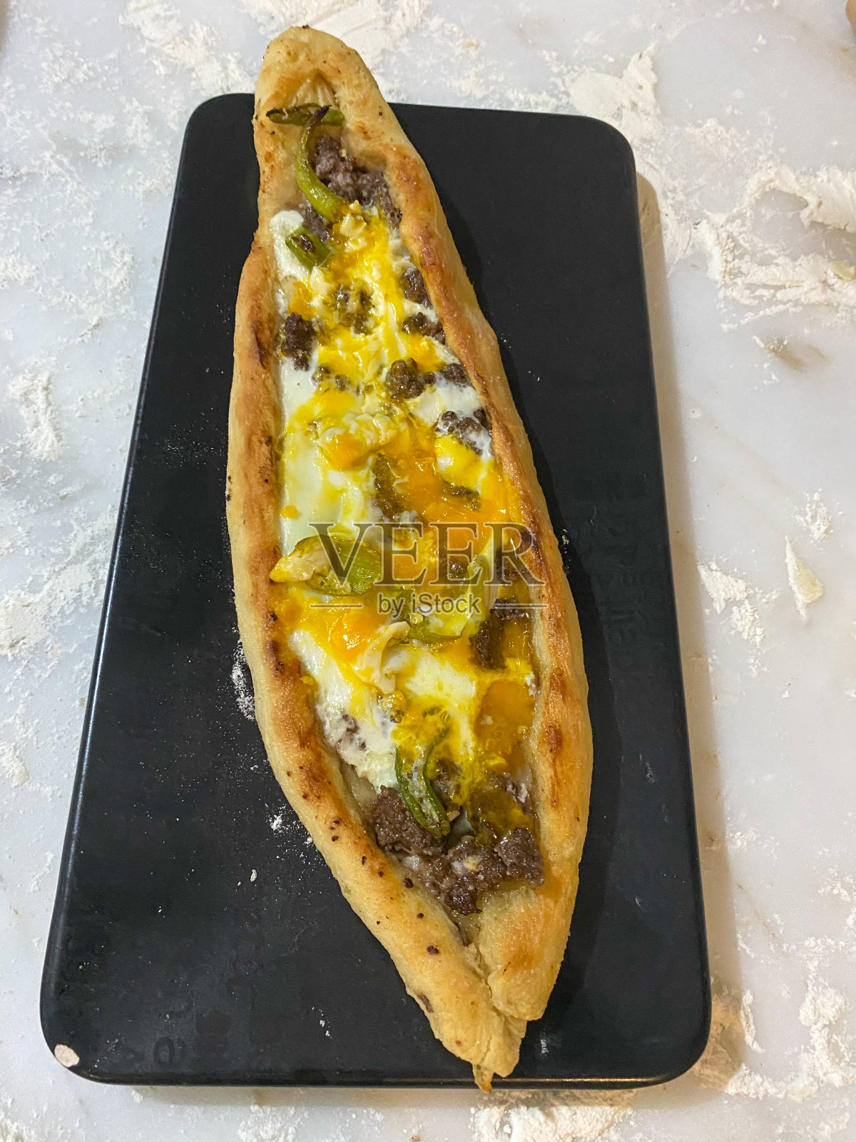 土耳其馅饼或土耳其披萨，扁平的面包，两端都有肉末，上面放着蔬菜、奶酪和鸡蛋照片摄影图片