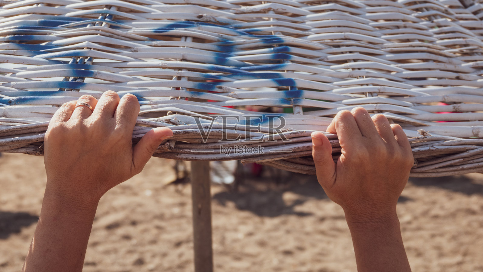 沙滩上的女性双手撑着柳条沙滩伞照片摄影图片