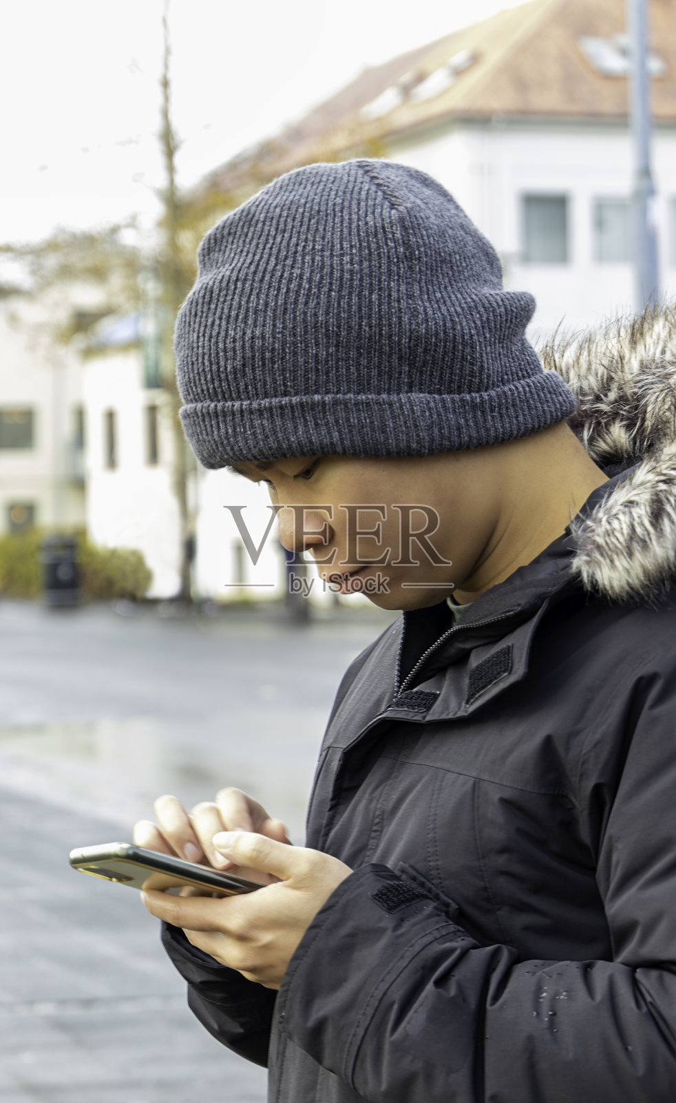 穿着保暖衣服的年轻人在看智能手机照片摄影图片
