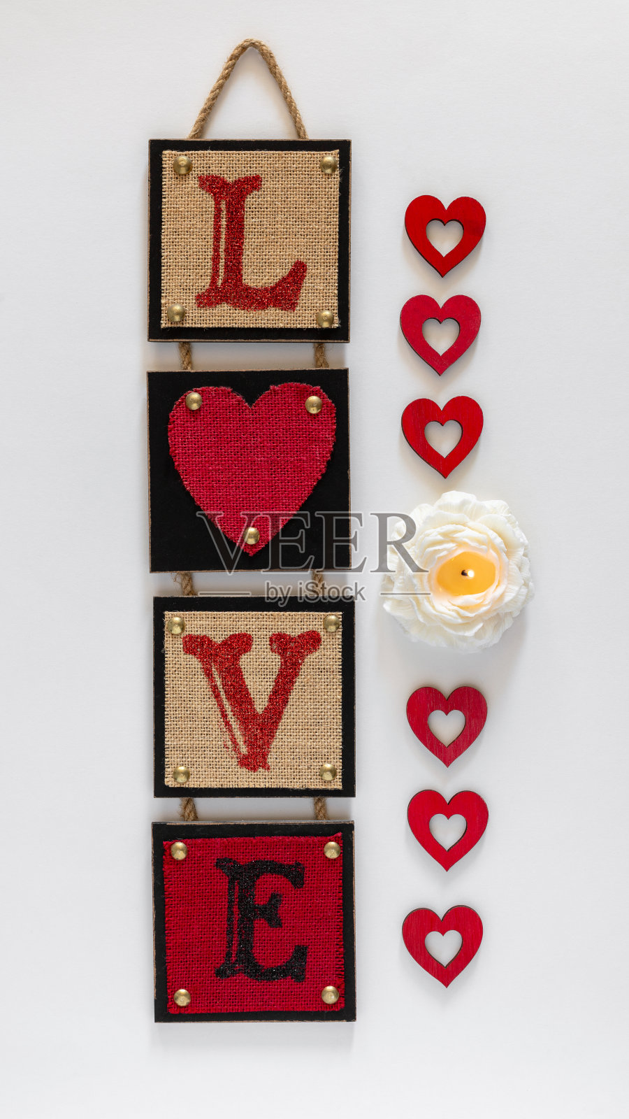 红色的墙壁装饰着“爱”字，燃烧着鲜花蜡烛和爱心。情人节和爱情的概念。照片摄影图片