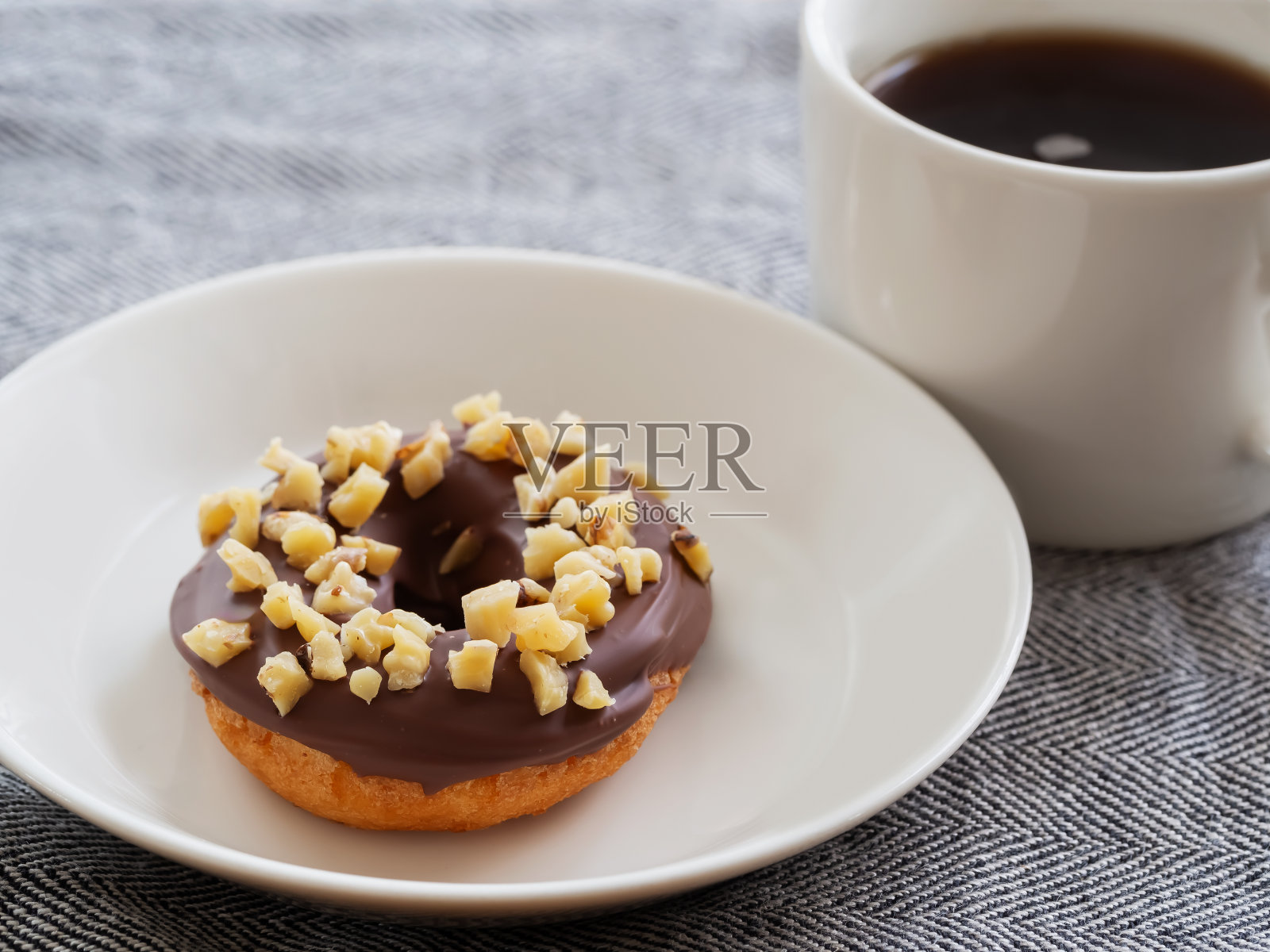 一个甜甜圈，上面有巧克力糖霜和核桃照片摄影图片