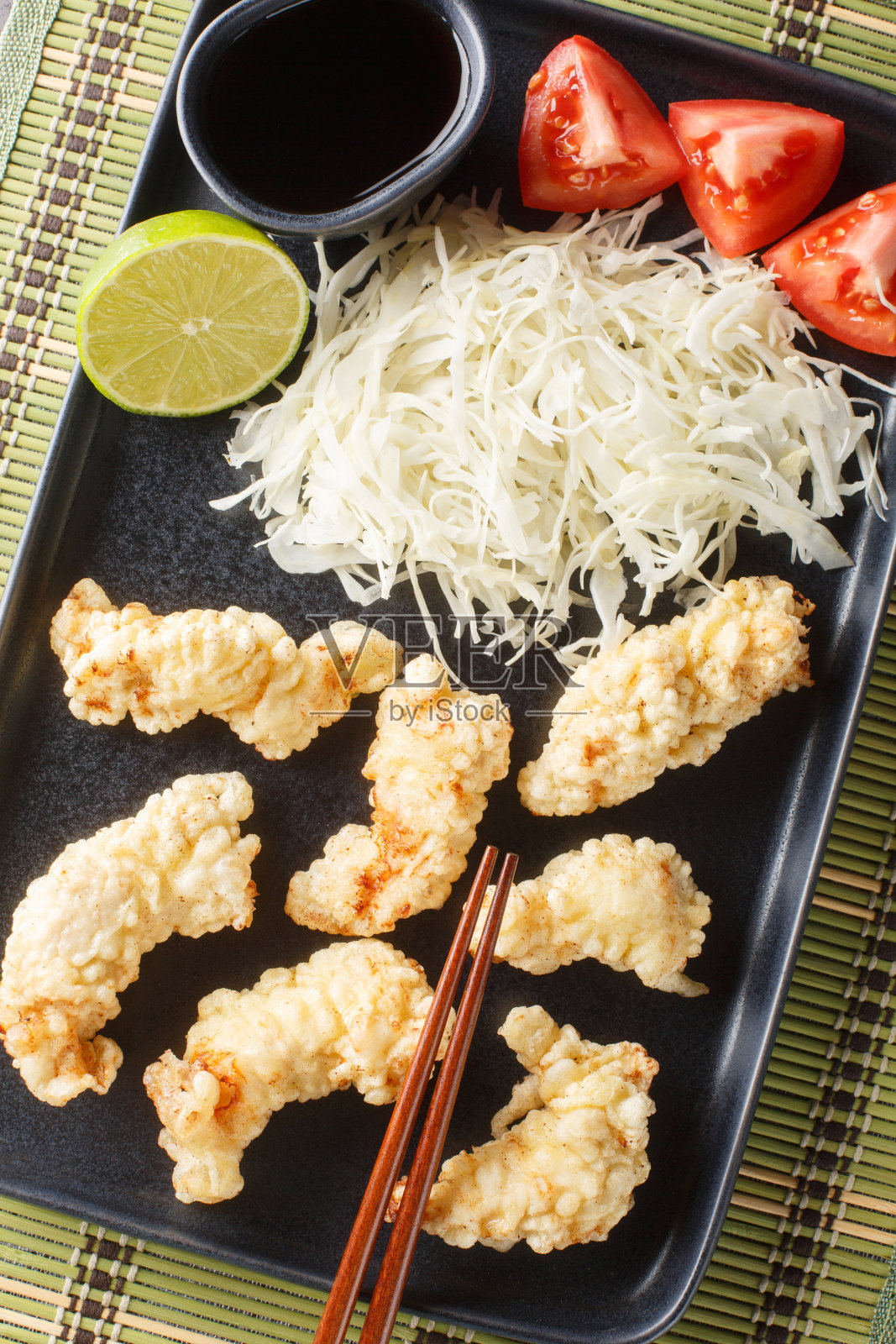 Toriten是一种日式天妇罗风格的炸鸡配上酱汁和卷心菜沙拉(特写)放在餐桌上的盘子里。垂直俯视图照片摄影图片