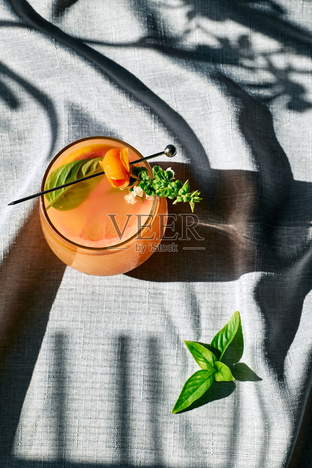 夏季清爽的葡萄柚饮料或葡萄柚片，冰和香草的酒精鸡尾酒。柑橘排毒饮料。照片摄影图片