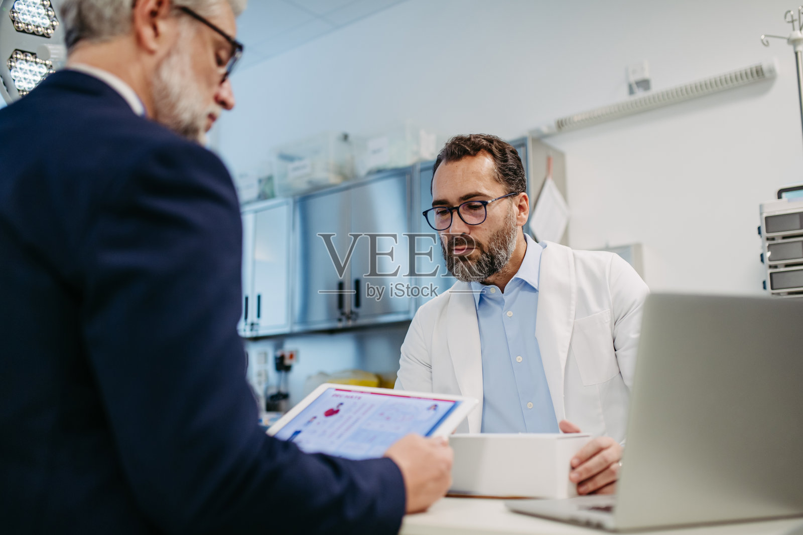 医药销售代表在医疗大楼向医生展示新药，手里拿着装有药物样品的盒子。照片摄影图片