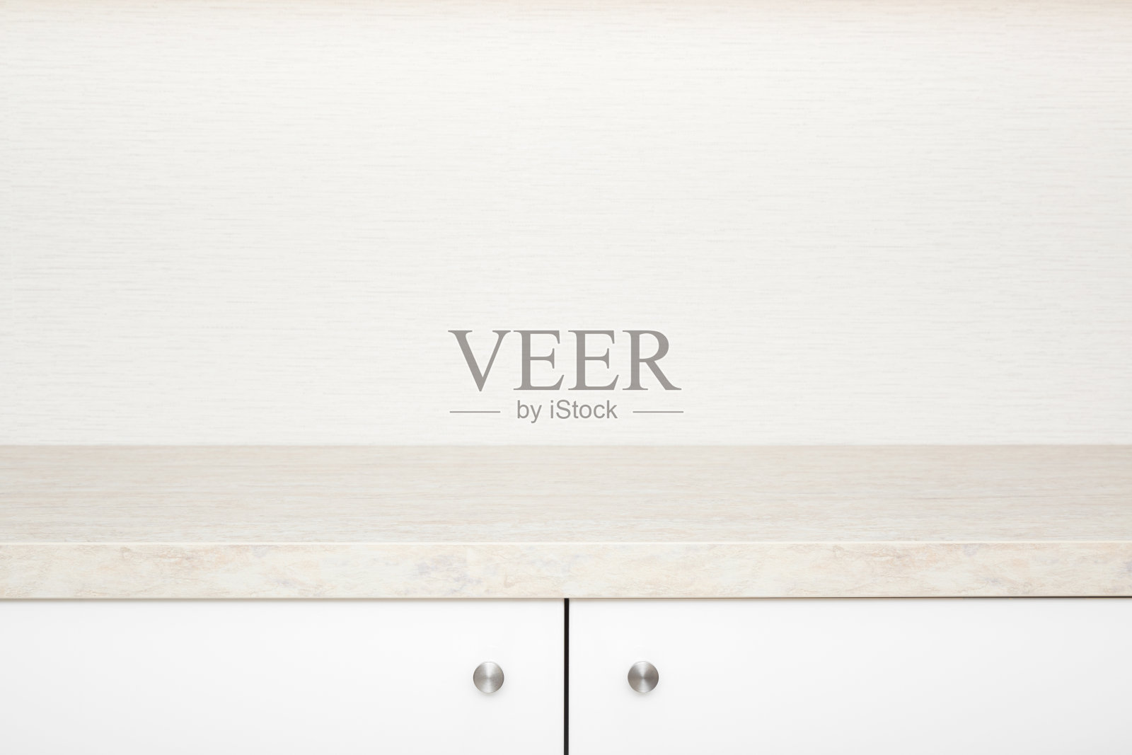 白色的橱柜门，在石桌面下有不锈钢把手。新的厨房家具。特写镜头。前视图。米色壁纸背景上的文字空白位置。照片摄影图片