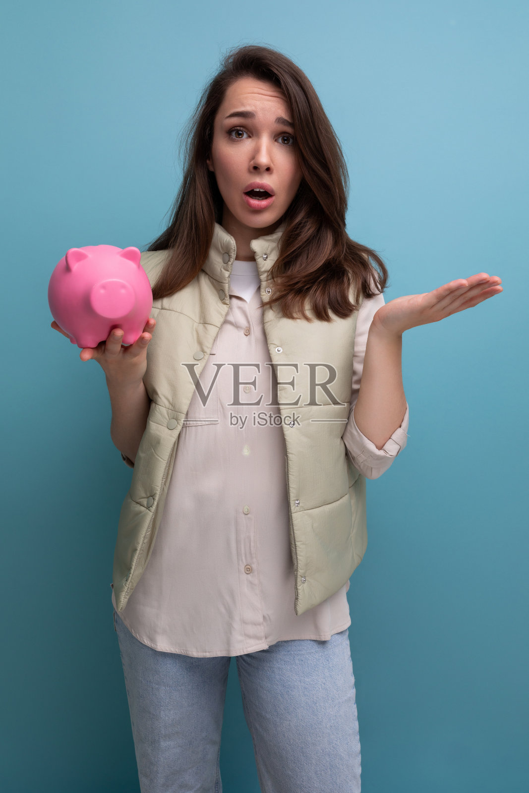 年轻的黑发女人把她的积蓄放在存钱罐里照片摄影图片