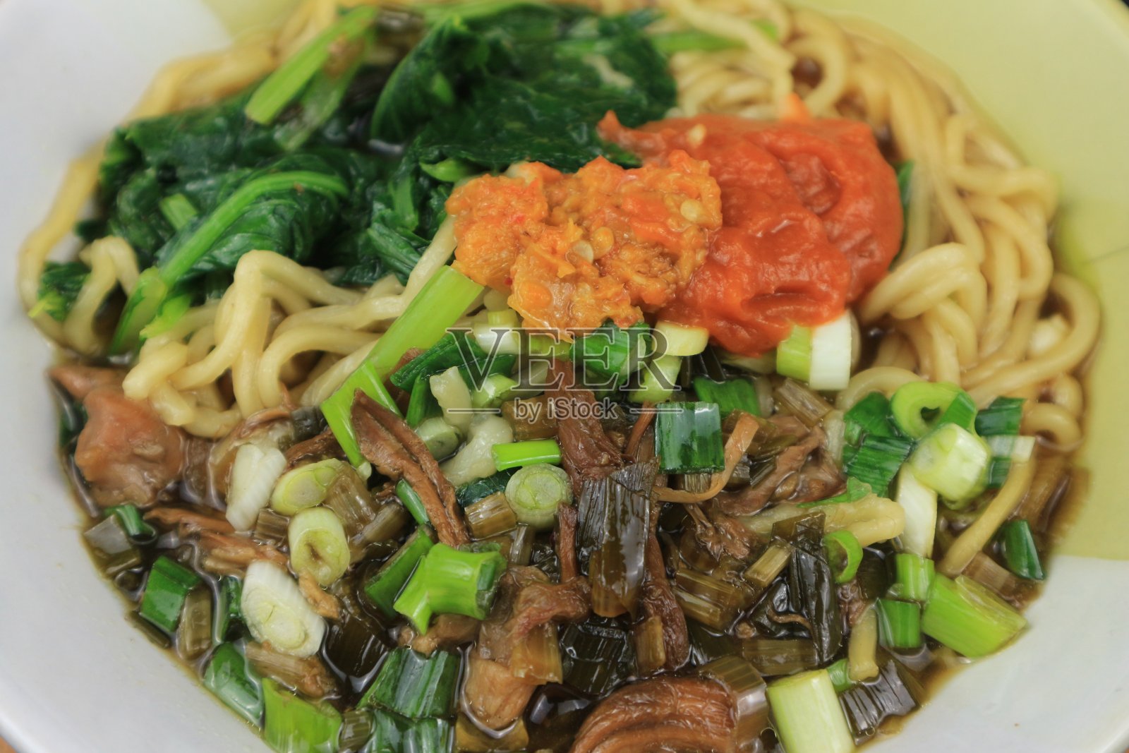 鸡面，印尼流行的街头小吃，盛在碗里，配上酱汁和辣椒酱照片摄影图片