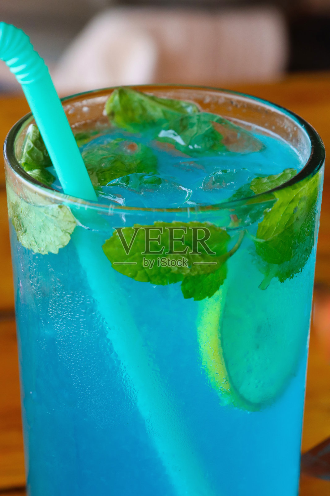 在露天海滩酒吧餐厅，蓝色泻湖伏特加和蓝色cura<s:1>鸡尾酒，柠檬片，薄荷叶，饮用吸管，餐厅设置背景木栏杆鸡尾酒的全帧图像照片摄影图片