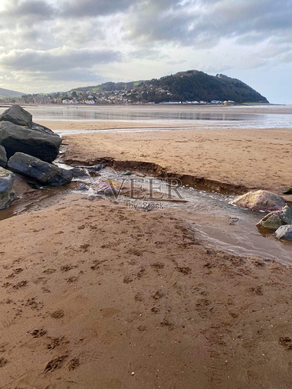 田园诗般的风景，沙滩与海岸线和小山的背景在英国镇。照片摄影图片