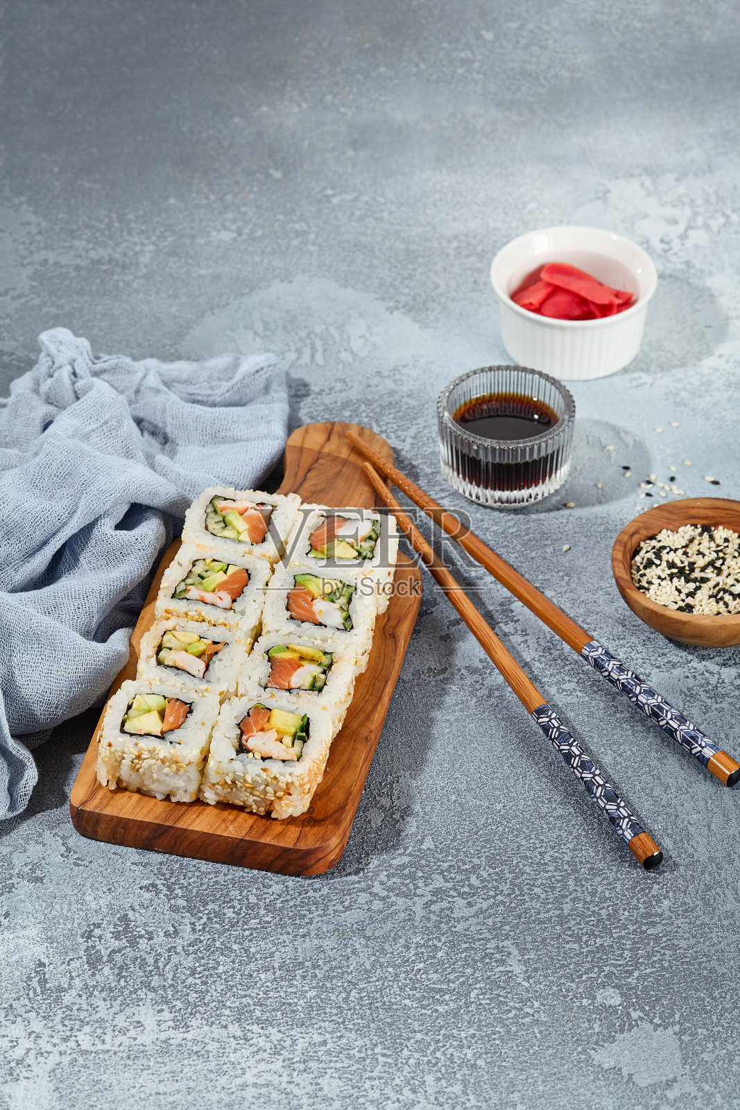 三文鱼，虾，鳄梨寿司卷和黄瓜在木制的服务板上照片摄影图片