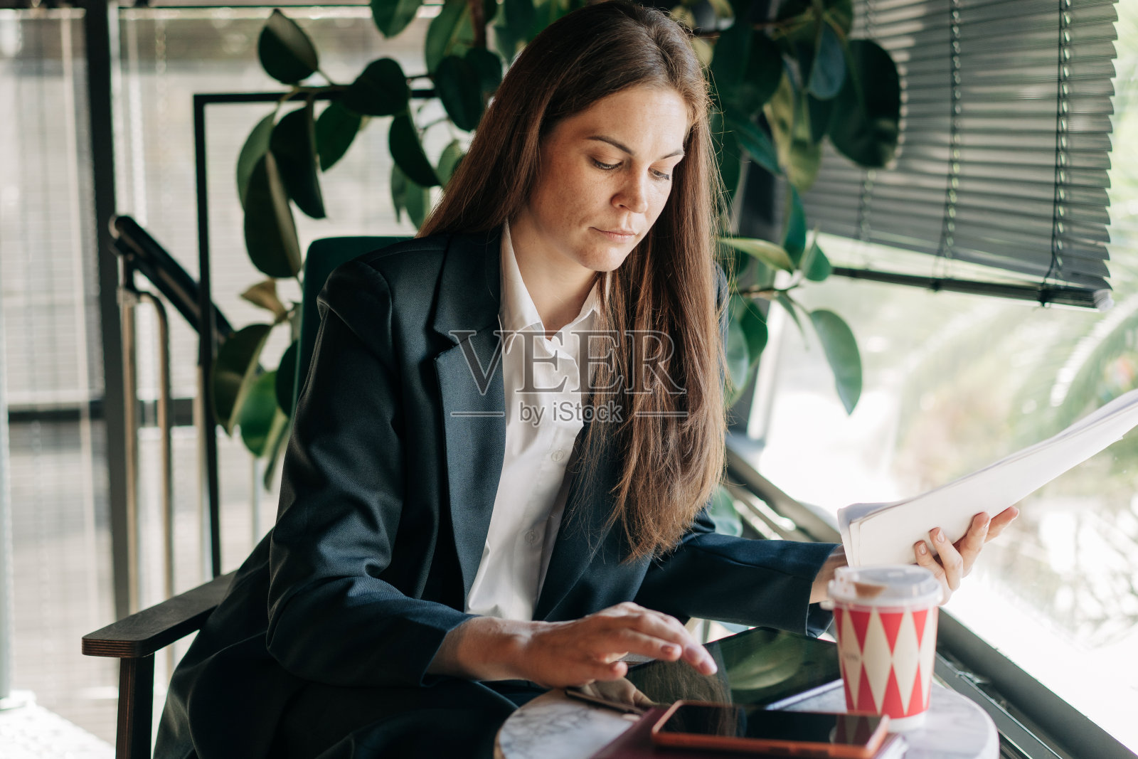 一位年轻的女商人在现代化的办公室里使用数字平板电脑处理会计和文件。照片摄影图片